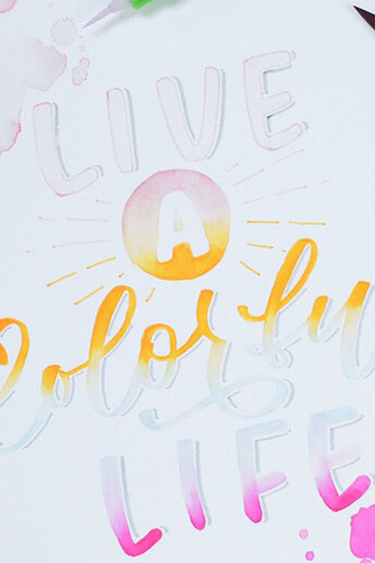 Een artistieke lettercompositie met waterverf en brush-pen techniek die dynamisch en expressief "Live a Colorful Life" ensceneert.