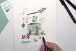 Een handgetekende, gekleurde illustratie toont een café (To Go) met een lantaarn, het jaar 2025 en de letters 新年 (Nieuwjaar). Een hand voegt details toe met een MONO tekenpen. Daarnaast liggen ABT Dual Brush Pens in de kleuren 192, 243 en 312 en een Waterbrush.