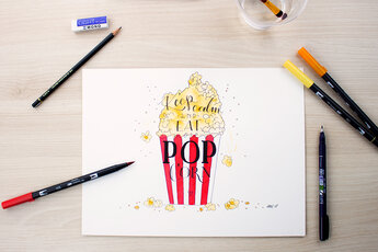 Handmade hand lettering with a red and white striped popcorn bag and the words "Keep calm and eat more popcorn", coloured with Tombow ABT Dual Brush Pens. Surrounded by a pencil, eraser and several Tombow pens.