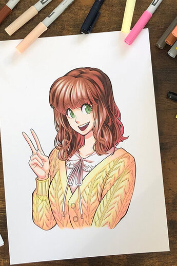 Een kleurrijke mangatekening op Tombow Bristolpapier, omringd door Tombow ABT Brush Pens in een breed scala aan kleuren. De Tombow MONO Eraser en MONO Zero Precision Eraser werden gebruikt voor correcties, terwijl fineliners en potloden werden gebruikt voor schetsen en contouren.