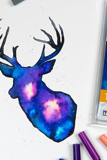 Een hertenmotief in een sterrenstelsel, ontworpen met Tombow ABT Dual Brush Pens. De felle blauwe, paarse en roze tinten creëren een dynamisch kleureffect, aangevuld met zwarte contouren en spikkels voor een kosmisch effect.